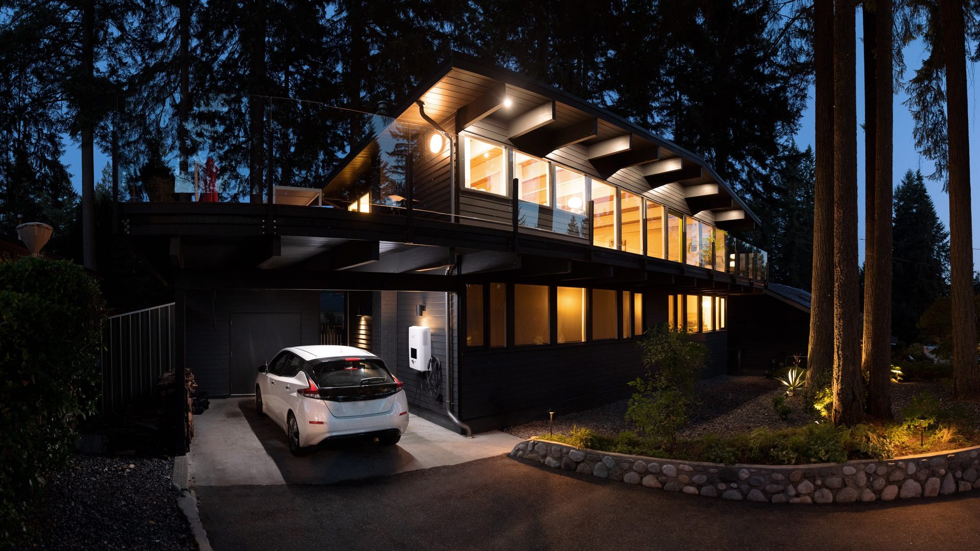 Haus mit E-Auto an der Wallbox im Carport